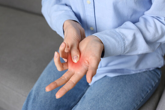 Woman suffering from trigger finger on sofa, closeup