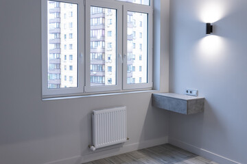 Modern apartment design. Window, floating bedside table, wall lighting and radiator