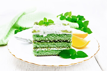 Cake with orange and mint in plate on light wooden board