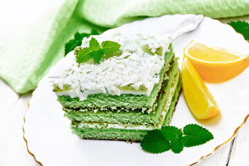 Cake with orange and mint in plate on white wooden board