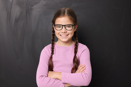Back to school. Cute girl in glasses near chalkboard