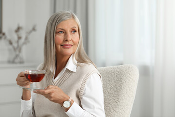 Portrait of beautiful middle aged woman with cup of tea at home, space for text