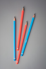 close-up of bunch of pencils, sharpened wooden blue and orange color unused pencils scattered and isolated on neutral gray background, stationery or writing and drawing instruments concept