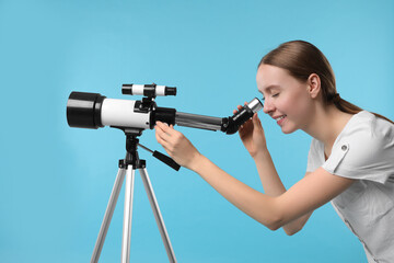 Young astronomer looking at stars through telescope on light blue background