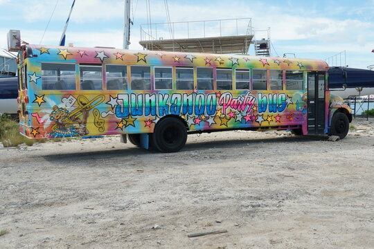Nassau, Bahamas 12 03 2023: Yellow school bus painted with graffiti and used in the past as party bus parked in scrapyard in Nassau, Bahamas. Vehicle is broken and out of order.