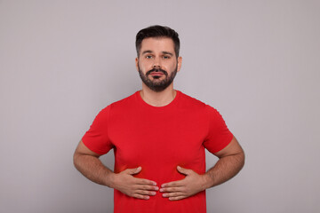 Man suffering from stomach pain on grey background