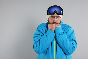 Winter sports. Man in ski suit and goggles on gray background, space for text