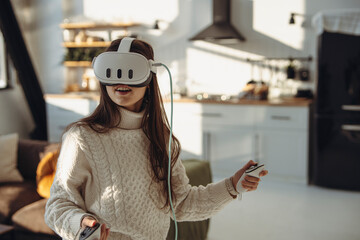 In a sunny ambiance, a lively young girl uses a virtual reality headset. - 706083907