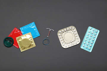 Contraceptive pills, condoms and intrauterine device on grey background, flat lay. Different birth...