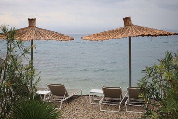 Beautiful straw umbrellas and sunbeds near sea