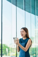 Asian Businesswoman Showing a Successful Yeah while Using Phone in a Modern Office Building in Downtown