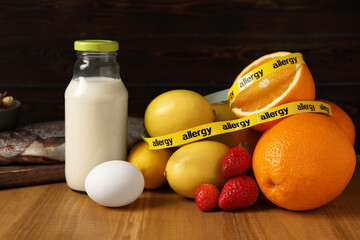 Allergenic food. Different fresh products with tape on wooden table, closeup