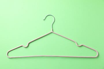 One pink hanger on light green background, top view