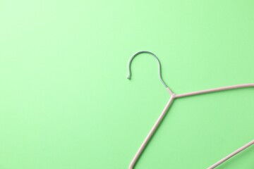 One pink hanger on light green background, top view. Space for text