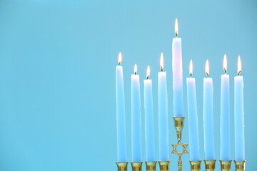Hanukkah celebration. Menorah with burning candles on light blue background, closeup and space for text