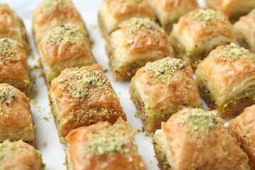 Delicious fresh baklava with chopped nuts on white table, closeup. Eastern sweets