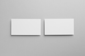 Blank business cards on light gray background, top view. Mockup for design