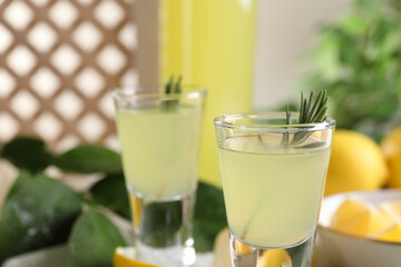Tasty limoncello liqueur with rosemary on table, closeup. Space for text