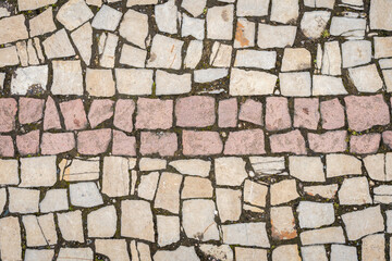 A road paved with stones, a green grass between stones on the sidewalk