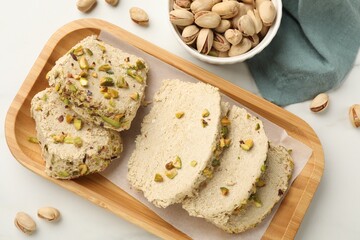 Tasty halva with pistachios on white table, top view