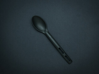 A large black silicone spoon on a black background.