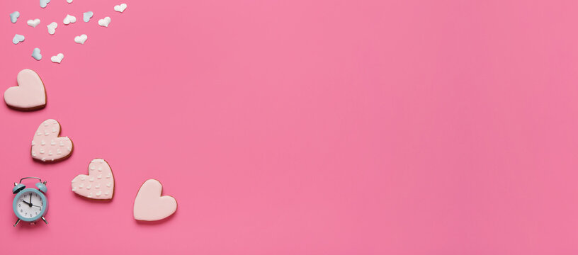 Heart shaped sweet cookies with confetti and alarm clock on pink background with space for text. Valentine's day celebration