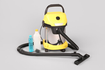 Vacuum cleaner with supplies on grey background