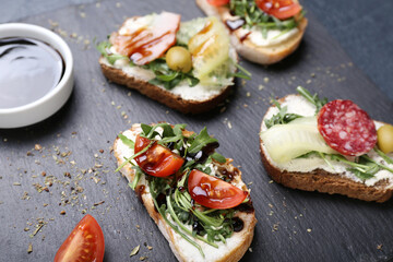 Slate board with tasty sandwiches and sauce, closeup