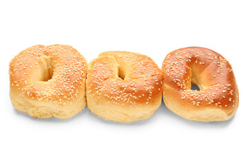 Tasty bagels with sesame seeds on white background