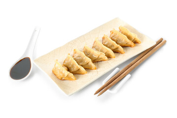 Plate with tasty Chinese jiaozi and sauce on white background