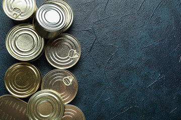 Assortment of tin cans with fish on dark table