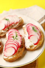 Plate with delicious radish bruschettas on yellow background