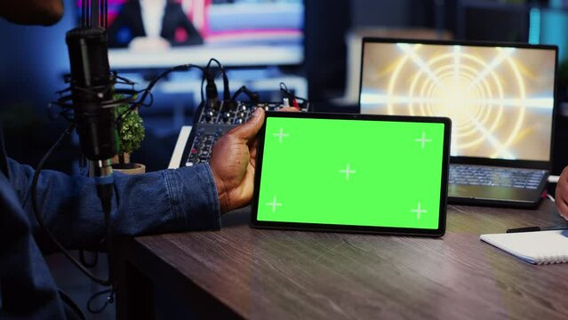 Man invited to podcast watching internet clips on green screen tablet with host in living room studio. Guest and presenter reacting to videos on mockup device during online comedy show, close up