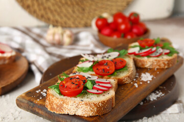 Board with delicious radish bruschettas on white table