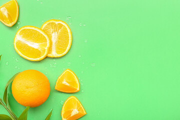 Cut orange with plant branch and water drops on green background