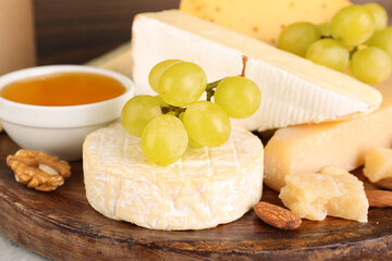 Plate with tasty cheese and grapes on table, closeup