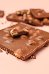 Sweet tasty chocolate with nuts on  light pink background, closeup