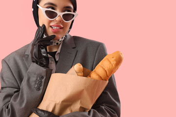 Stylish young woman in leather gloves with baguettes on pink background, closeup