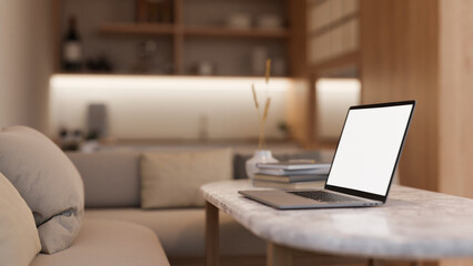 Side view image of a white-screen laptop computer on a coffee table in a modern and cosy living room