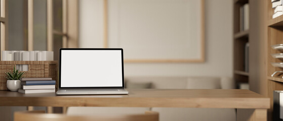 A white-screen laptop computer mockup on a wooden desk in a modern, Scandinavian room.