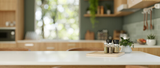 Spices bottles and a copy space on a dining table in a modern green and wood kitchen.