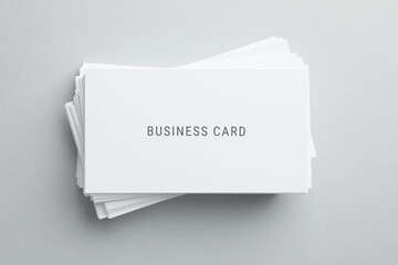Stack of business cards on light grey background, top view