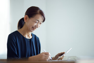 タブレット端末を使用して勉強をする日本人のシニア女性