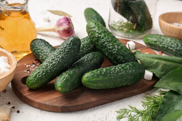 Wooden board with fresh cucumbers for preservation on light background