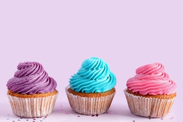 Tasty colorful cupcakes on purple background