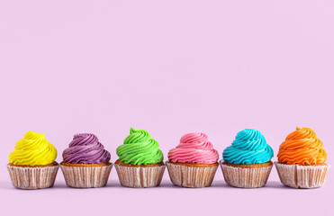 Tasty colorful cupcakes on purple background