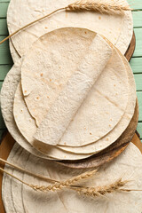 Wooden boards with fresh lavash on green wooden background