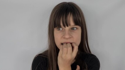 Cute little girl bites her nails, is nervous and anxious. Teenage child biting nails
