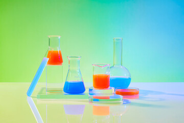Laboratory glassware containing color liquid displayed on transparent podiums on green gradient background. Blank space for display product with minimal concept
