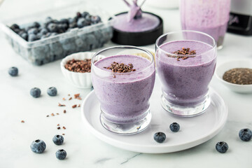 Glasses of freshly made healthy blueberry smoothie, topped with cacao nibs.